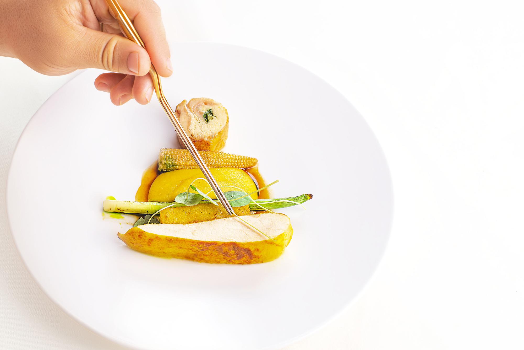 Close-up of plated dish being finished quickly
